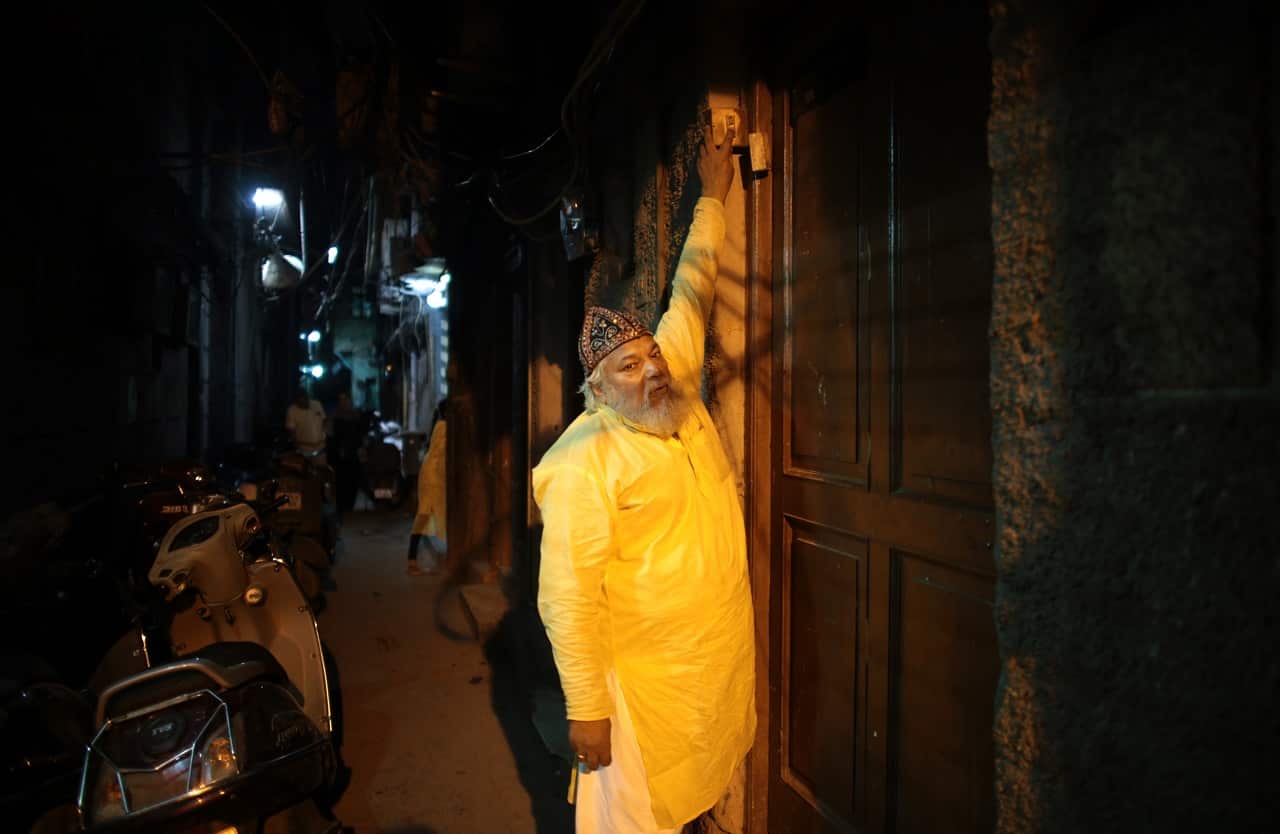 Mohammed Shafiq, a town crier, knocks on a door to wake neighbors for a pre-dawn meal during Ramadan in the Old Delhi quarter of New Delhi. 