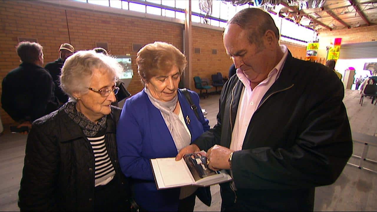 Former workers Lena Chomovska, Nada Bozhinovska and Jim Bozhinovski look at photographs 
