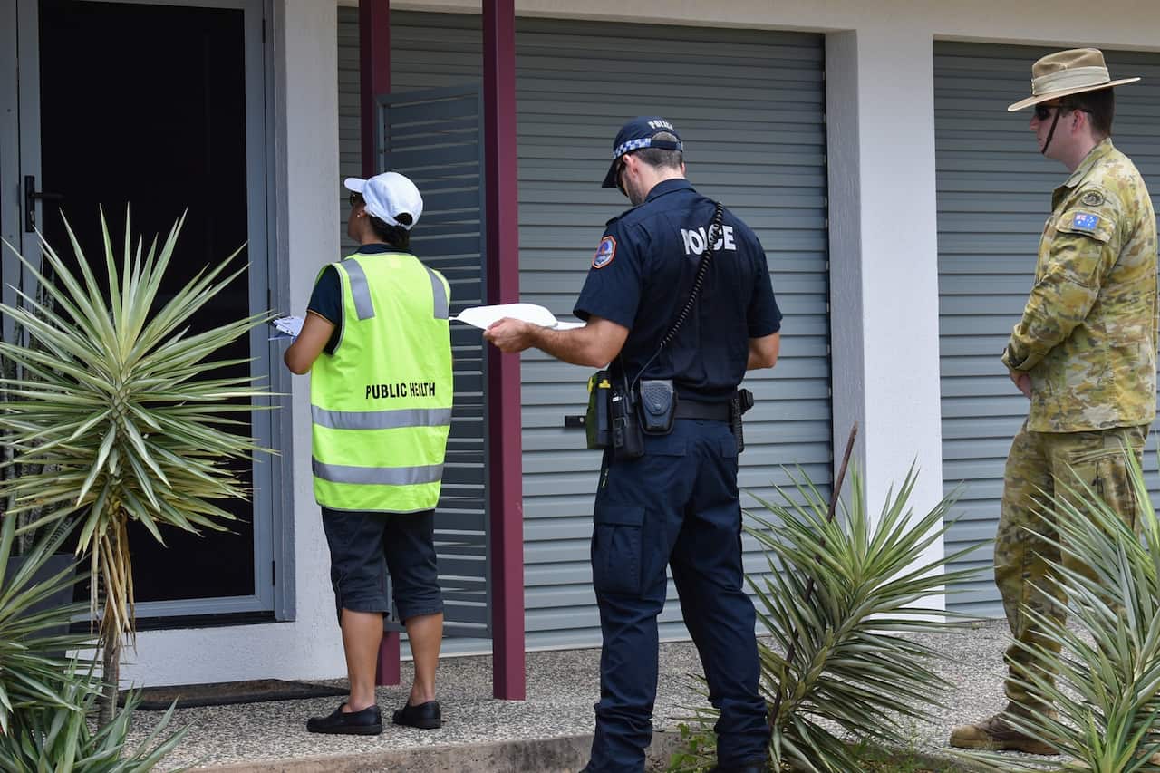 A public health officer, NT police officer and an Australian Defence Force member check in on those in self-isolation.
