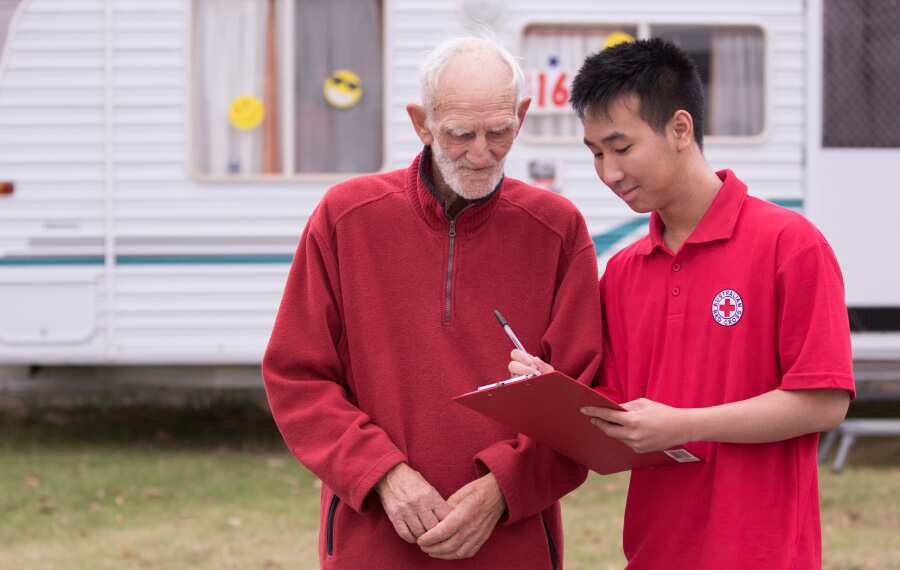 A member of the Australian Red Cross speaks with a bushfire survivor.
