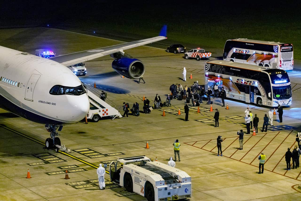Passengers from the Australian cruise ship Greg Mortimer, get on a plane to be flown to Australia at the international airport in Montevideo, Uruguay.