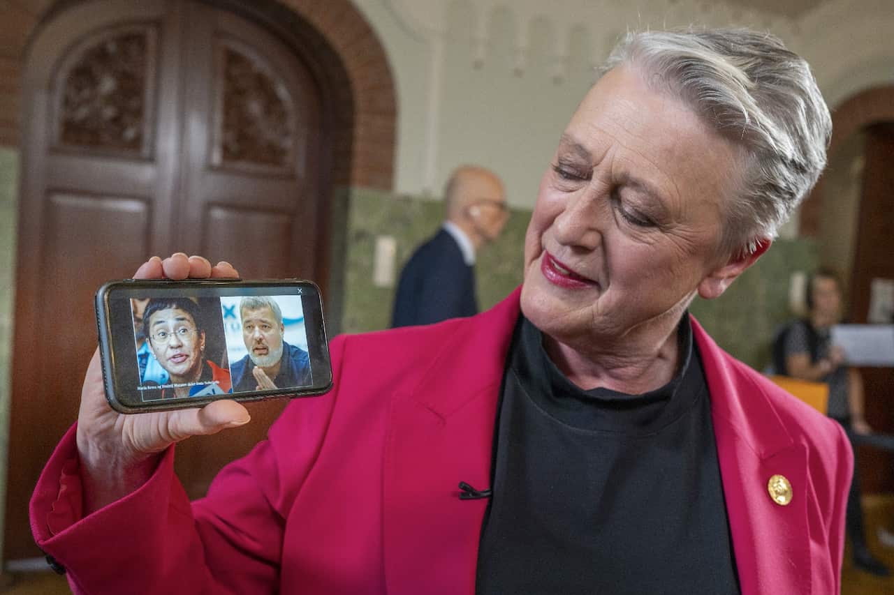 Norwegian Nobel Peace Prize Committee chairperson Berit Reiss-Andersen shows a photo of Peace Prize laureates Maria Ressa and Dmitry Muratov.