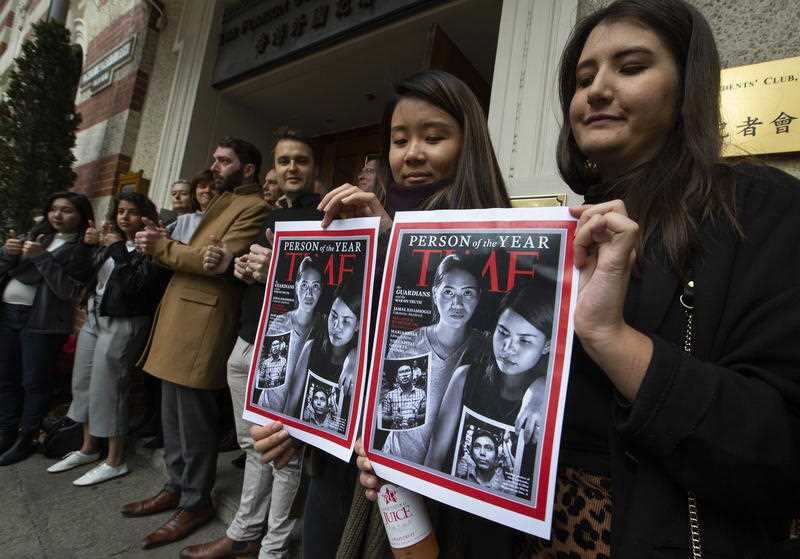 Press freedom activists hold copies of the front page of Time magazine's Person of the Year edition, highlighting the jailed journalists’ plight. 