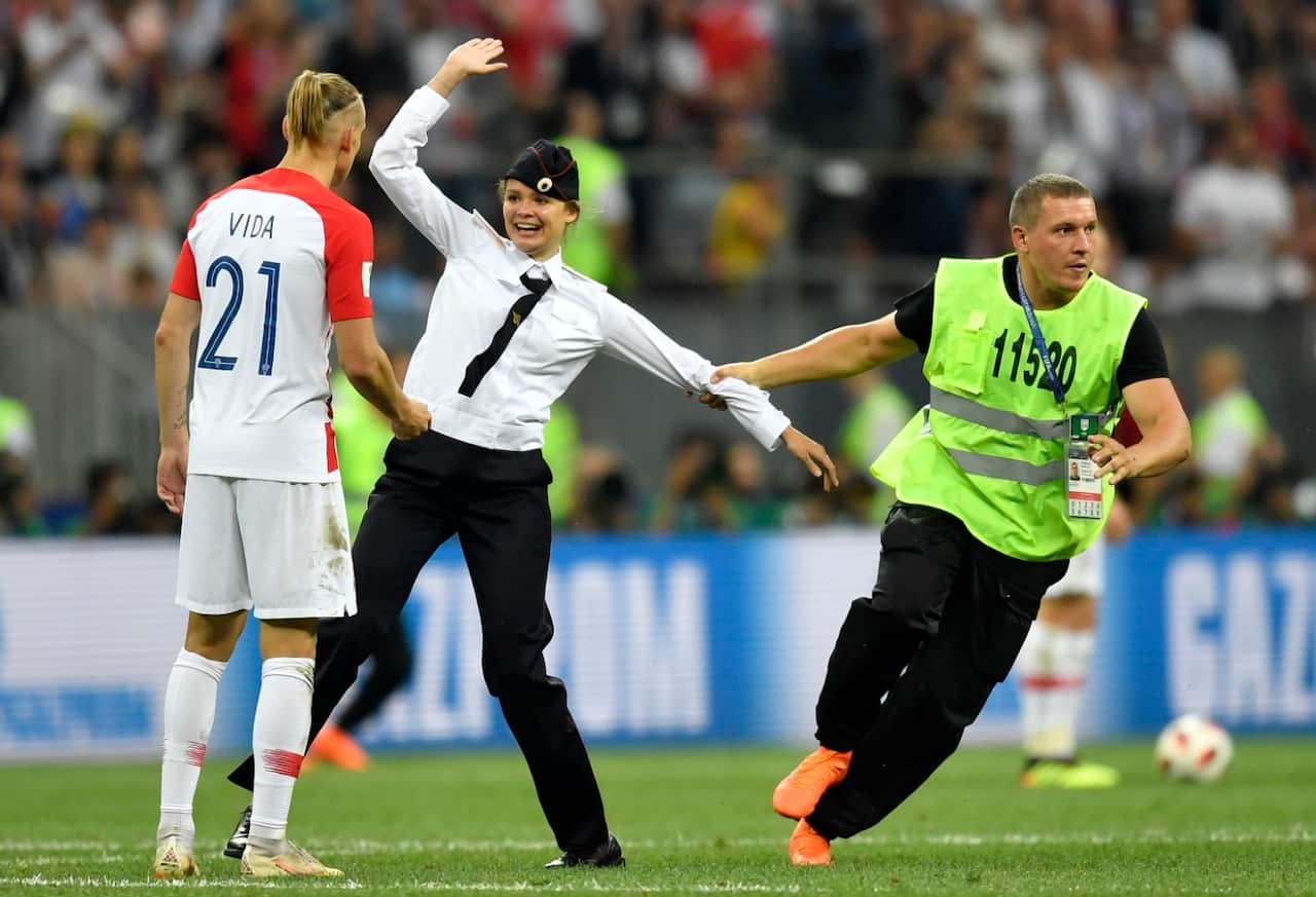 Stewards pull a woman off the pitch after she stormed onto the field and interrupted the final match