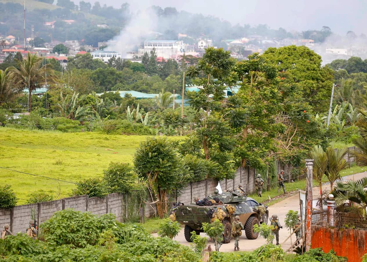 Fire rages at the suspected Muslim militant positions following airstrikes by helicopter gunships as Philippine marines walk to the frontline (AAP)