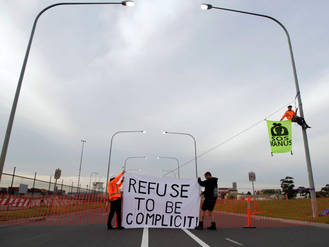 Activists block a Melbourne port container and unfurl banners.