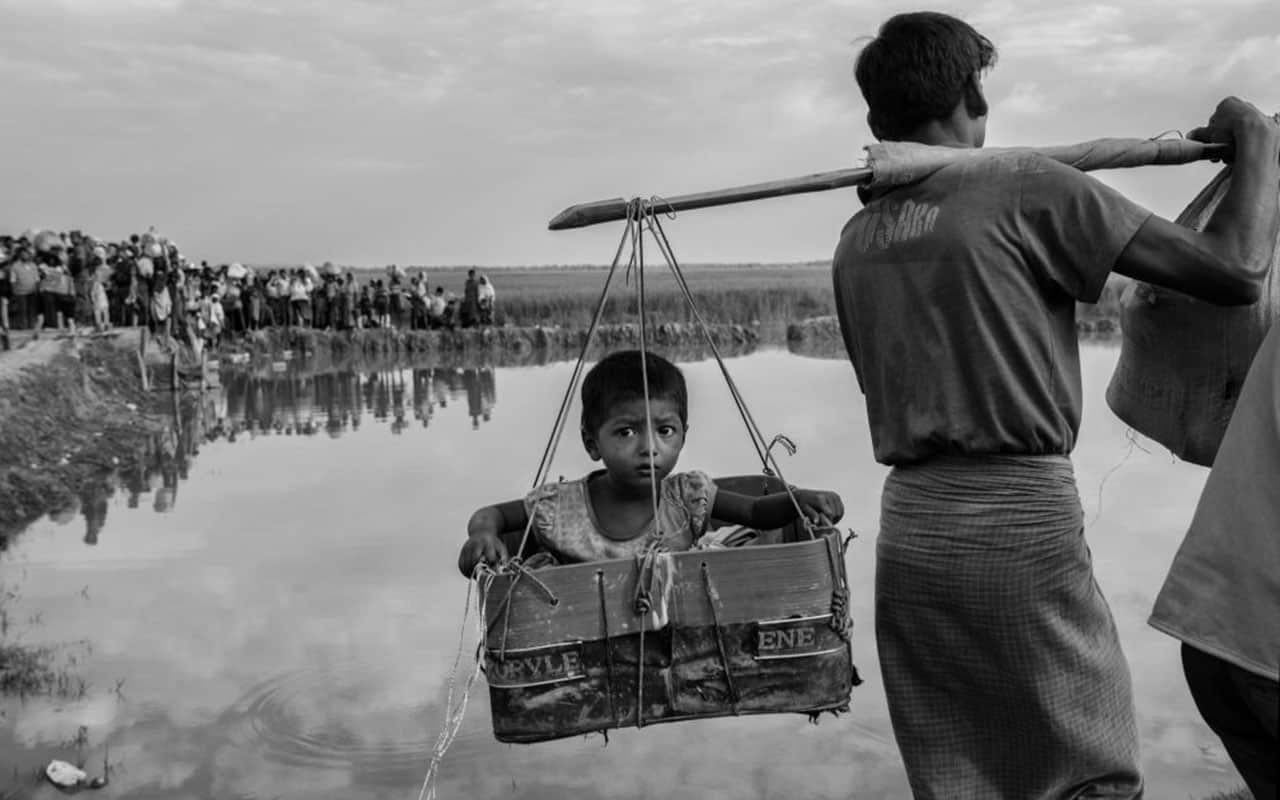 A Rohingya Muslim refugee boy is carried in a basket after crossing the border from Myanmar into Bangladesh