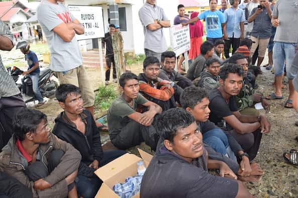 Suspected Rohingya people sit on the ground as they arrive in Idi Rayeuk, East Aceh on December 4.