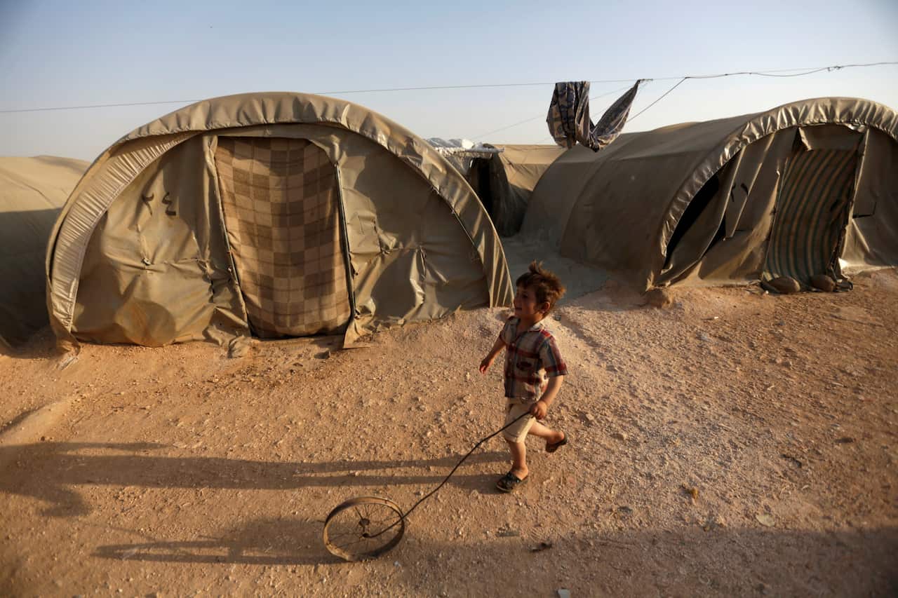A boy plays with a wheel at a camp for internally displaced people in Syria.