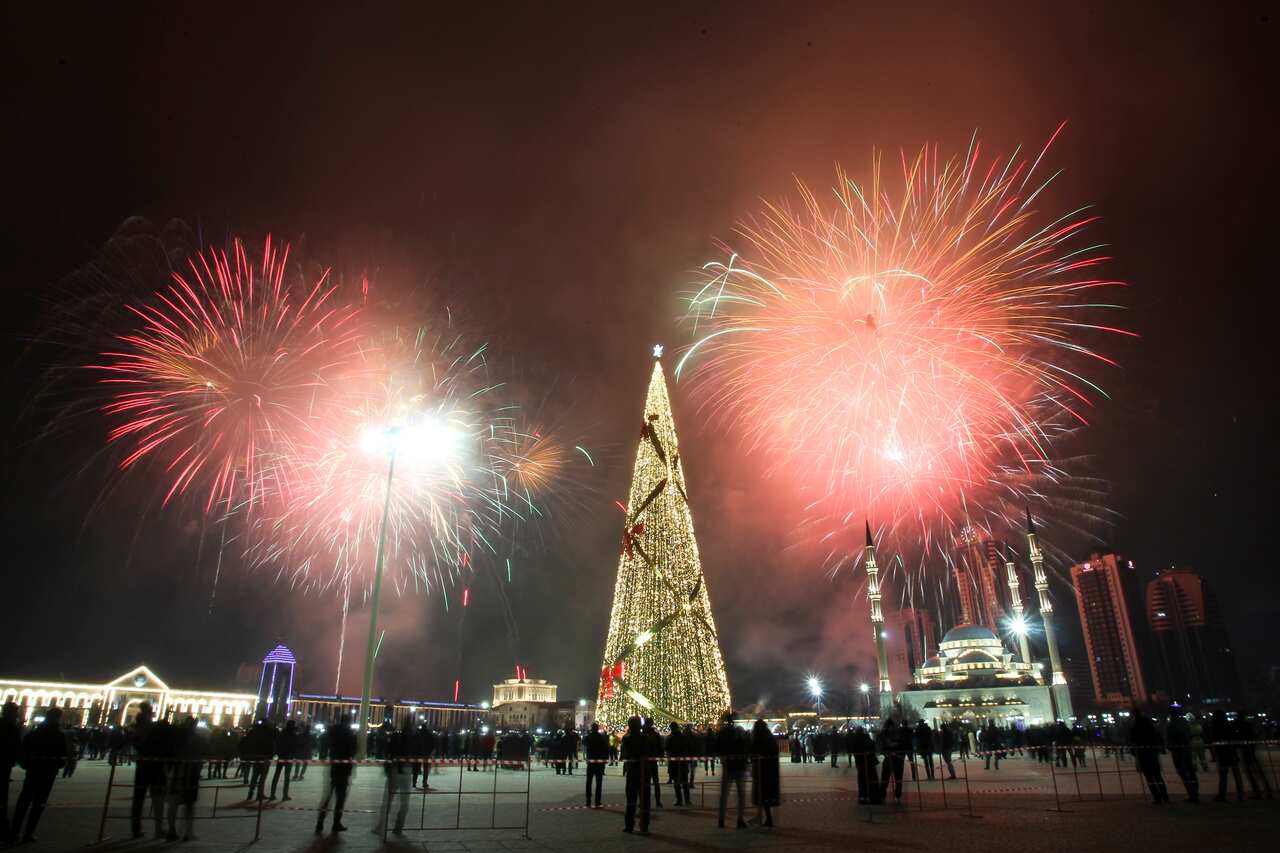 Fireworks explode over a not-too-crowded square with a Christmas tree and skyscrapers during New Year's celebrations in Grozny, Russia.