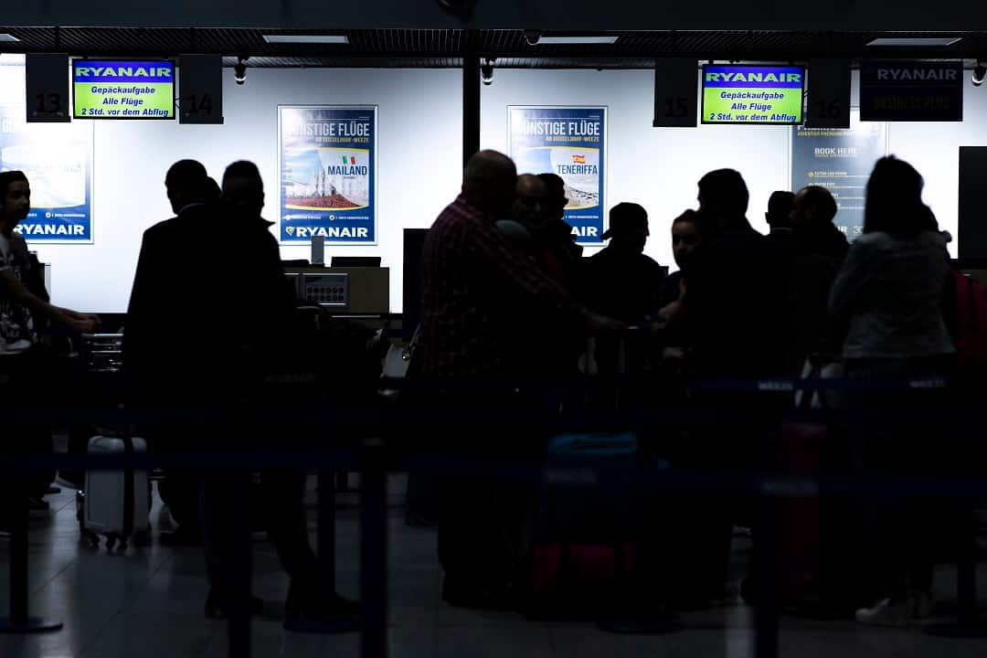 Passengers crowd around the empty Ryanair check-in counters.