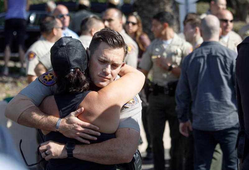 Deputies embrace after the hearse carrying the body of Sergeant Ron Helus arrives at the medical examiner's office in Ventura, California.