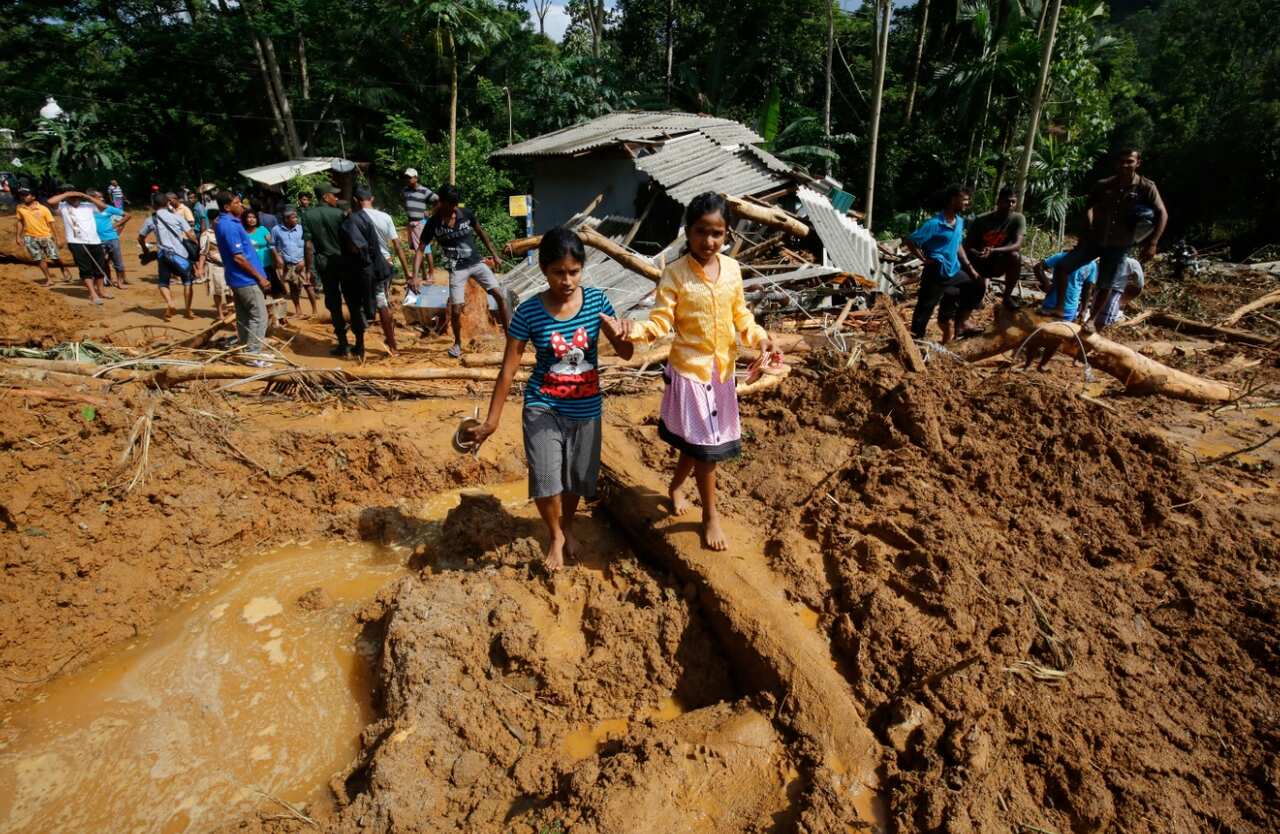 Children walk in mud where a landslide occured in which 35 people are feared killed at Athwelthote in Baduraliya (AAP)