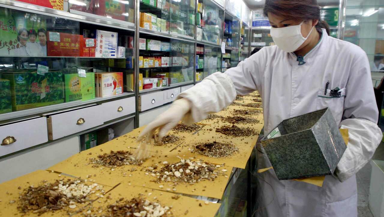 A Chinese woman at a pharmacy prepares Chinese medicine for the prevention of SARS infections in Beijing, China, 15 April 2003. 