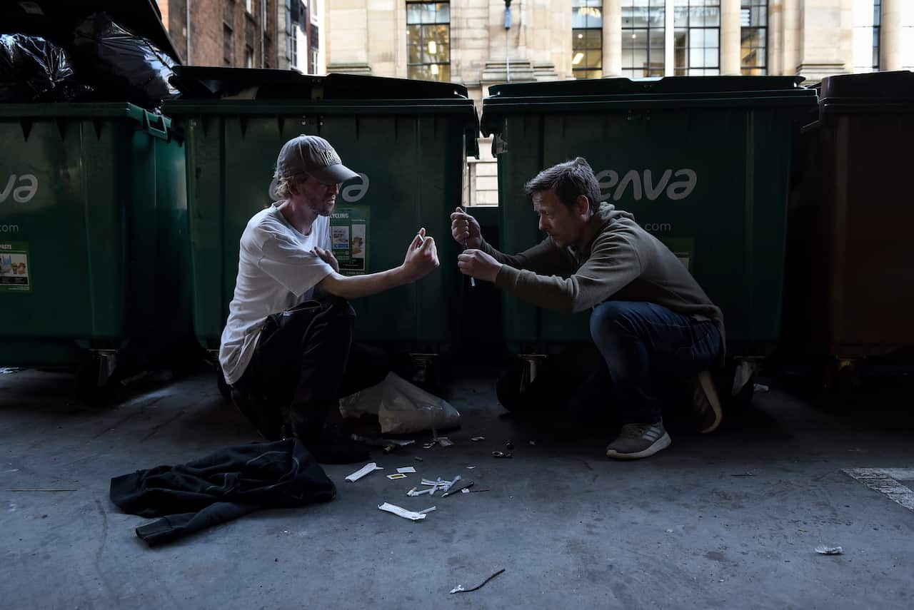 James Muir and Tony Nugent prepare to use heroin in a parking garage in Glasgow, Scotland, July 23, 2019. (Mary Turner/The New York Times)