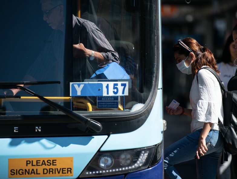 A woman gets on a bus in Sydney.