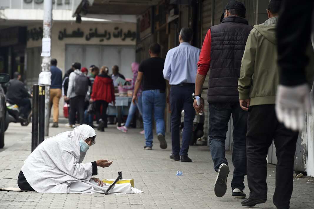 A woman begs on a street in Tripoli.