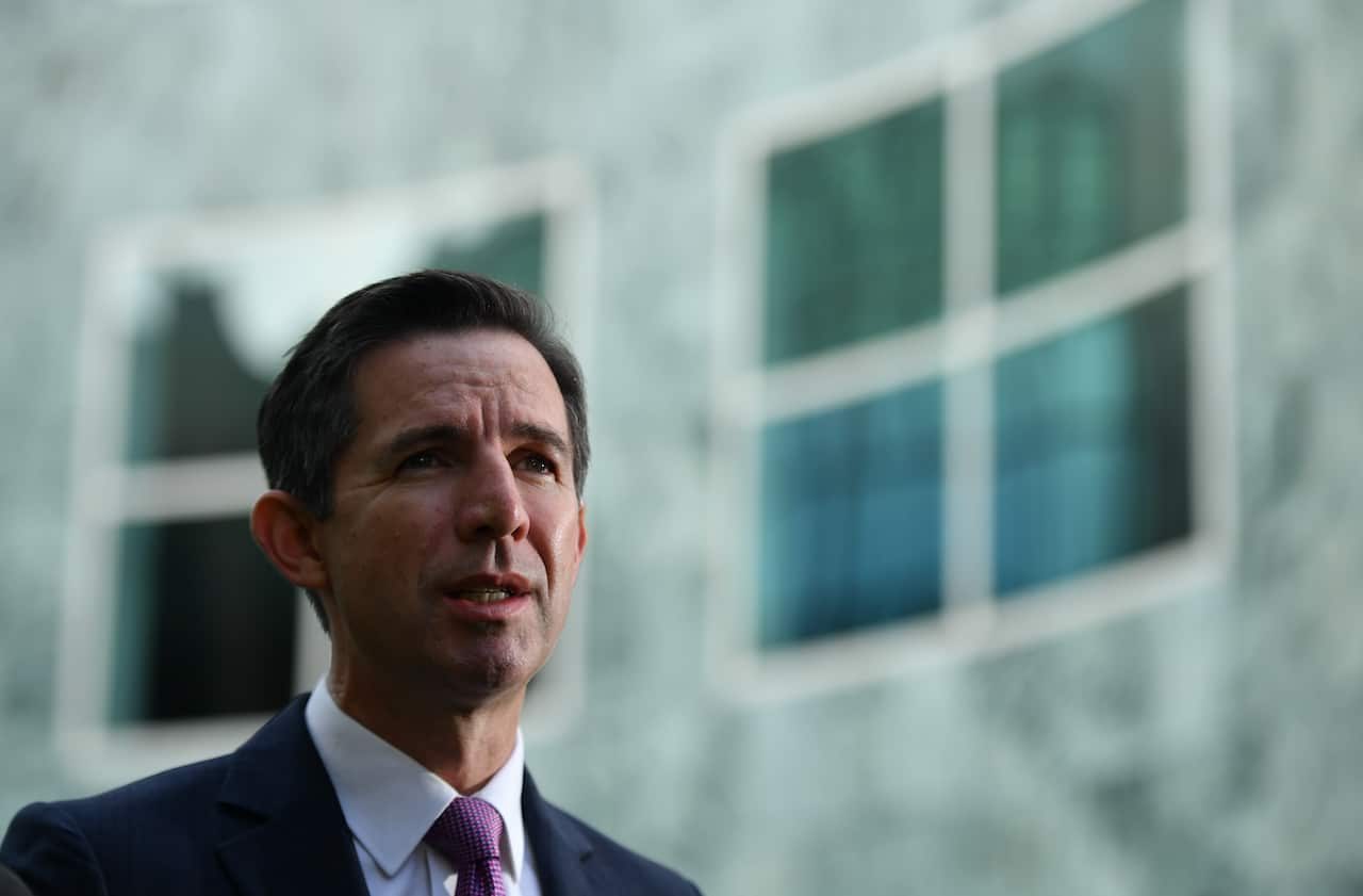 Man in suit and tie speaking in a courtyard.