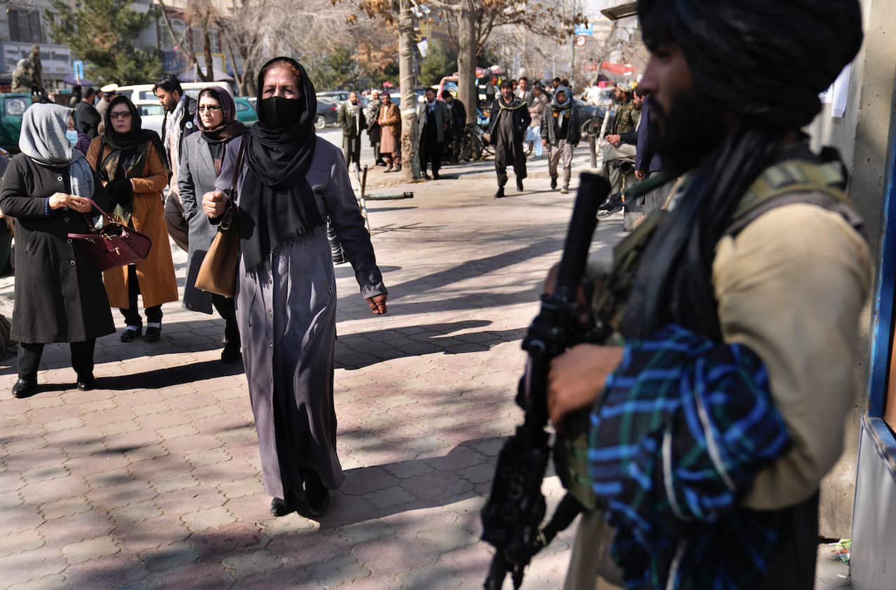Afghan women pass next of Taliban fighter in Kabul, Afghanistan, Sunday, 13 February, 2022. 