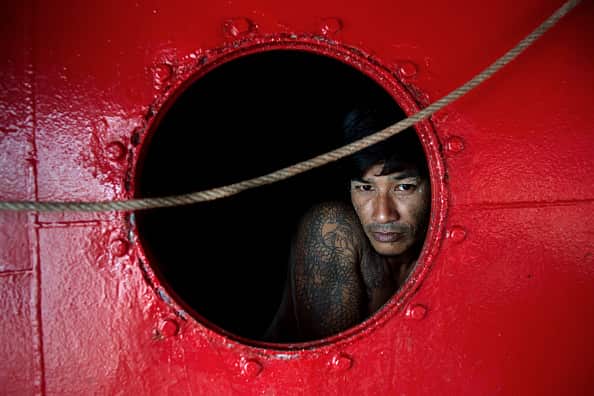 A migrant worker seen through a window of a fishing boat that is docked in Phuket.