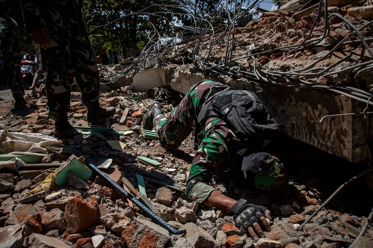 Indonesian soldiers look for victims at a collapsed house in Lombok following the Indonesian earthquake.