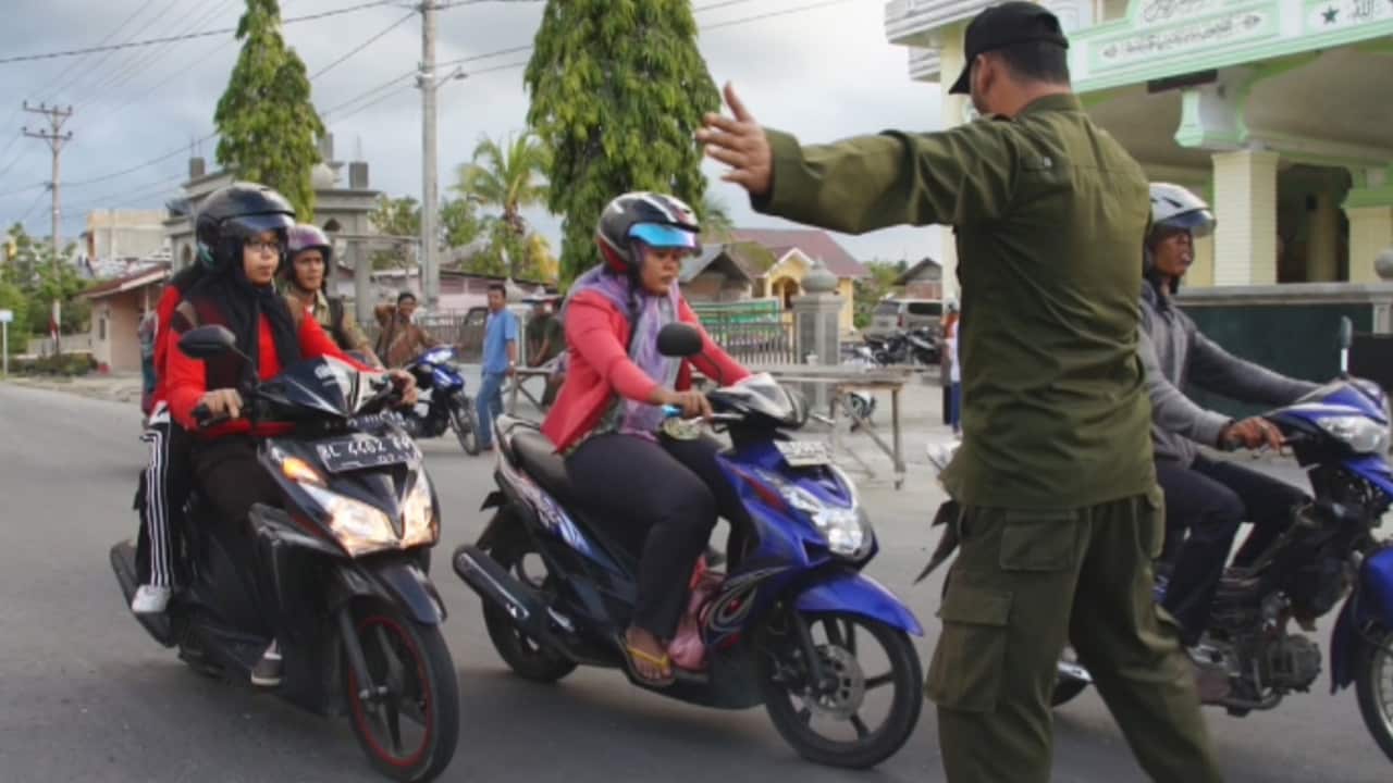 Sharia Police officers stop women at one of their checkpoints to ensure they're complying with the Islamic dress code.