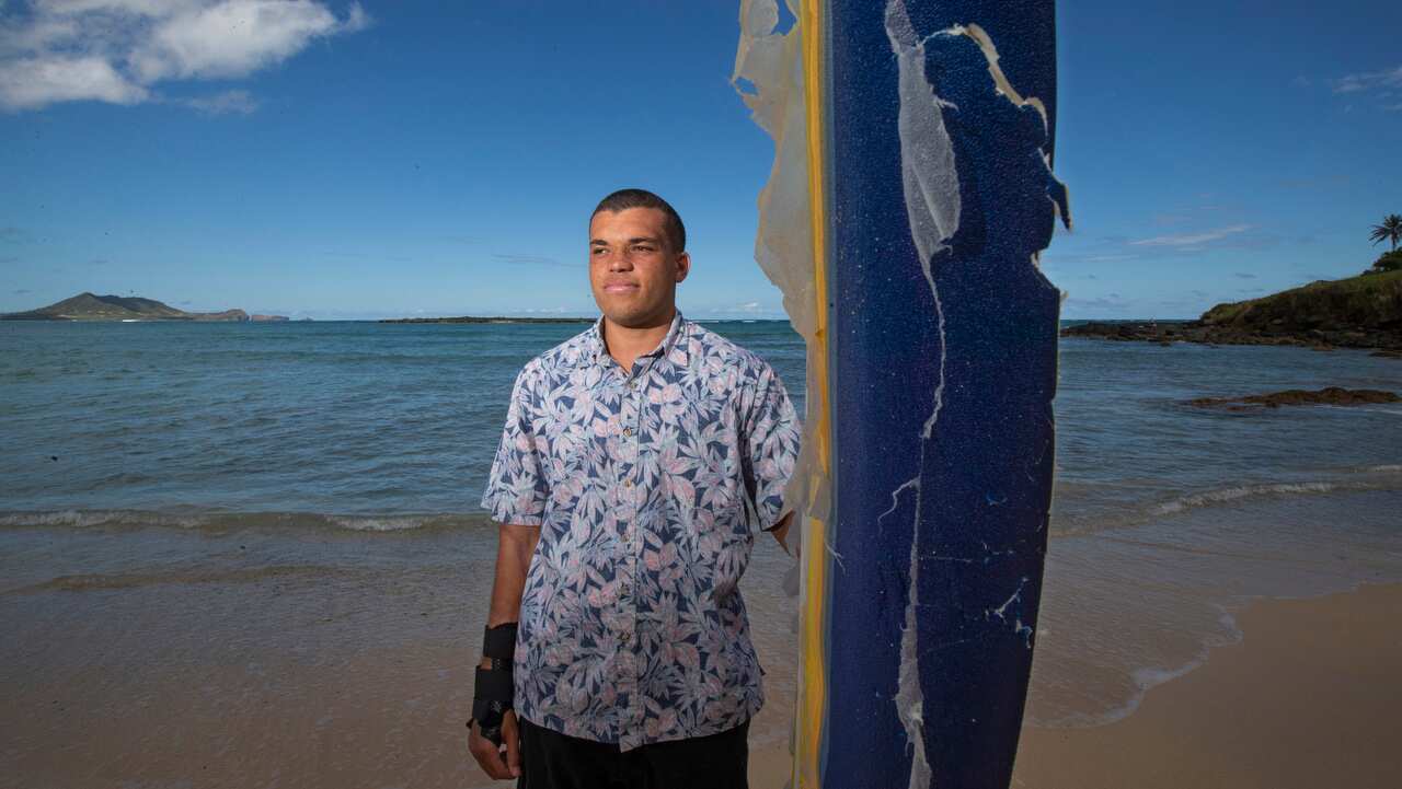 Juliun Perkins on Kailua beach with the surf board he was on during the attack in Laie.  