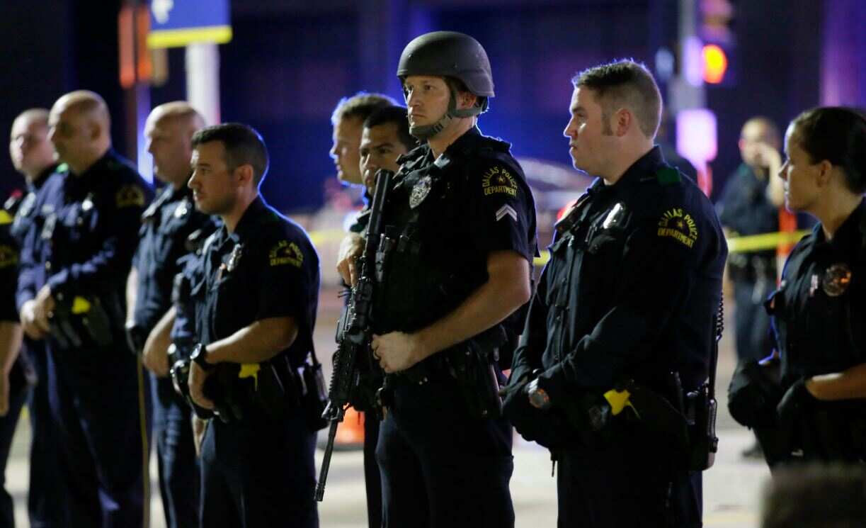 Armed dallas police officers form a line on the street.