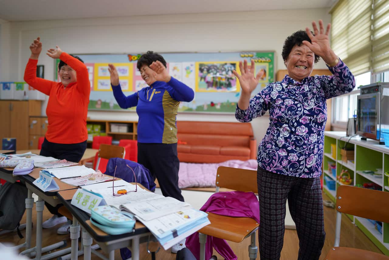 Hwang Wol-geum, 70, Kim Mae-ye, 64, and Park Jong-sim, 75, dance to a children's song at Daegu Elementary, in Gangjin County, South Korea.