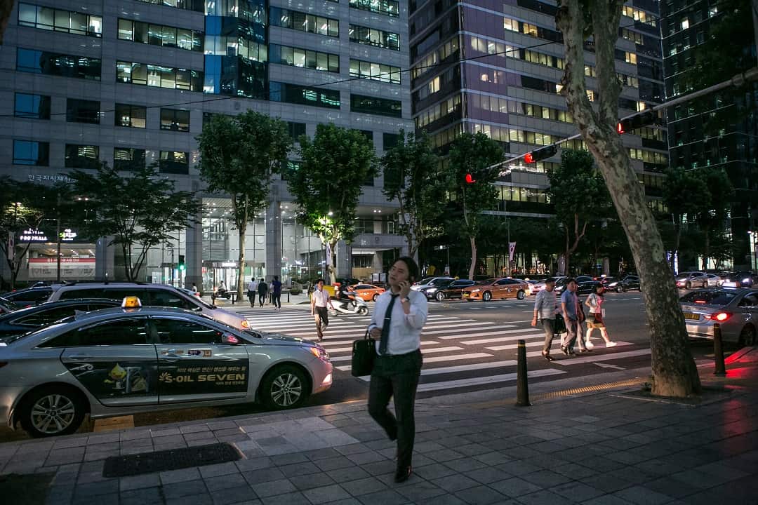 An office worker leaves for the day at 8 p.m. with many buildings still lit up in Seoul, South Korea.