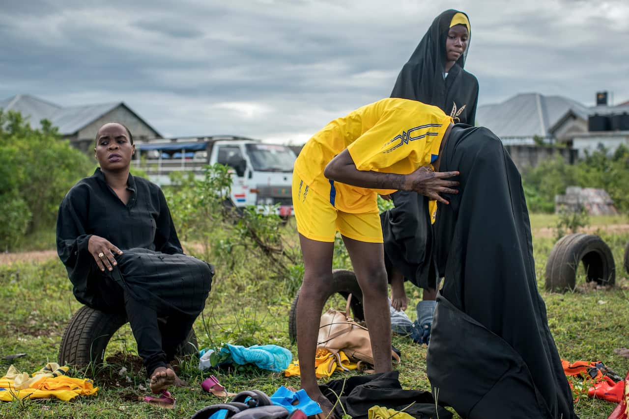 The Green Queens players change from the dark abayas they wear on the street into their uniforms before a soccer match, in Jumbi, Zanzibar.