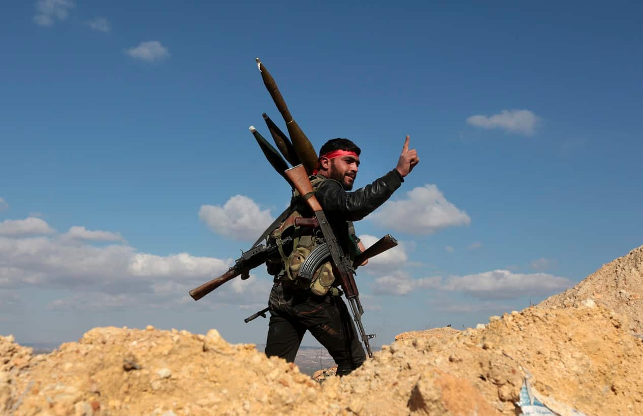 A pro-Turkey Syrian fighter waves on Bursayah hill, which separates the Kurdish-held enclave of Afrin from the Turkey-controlled town of Azaz.
