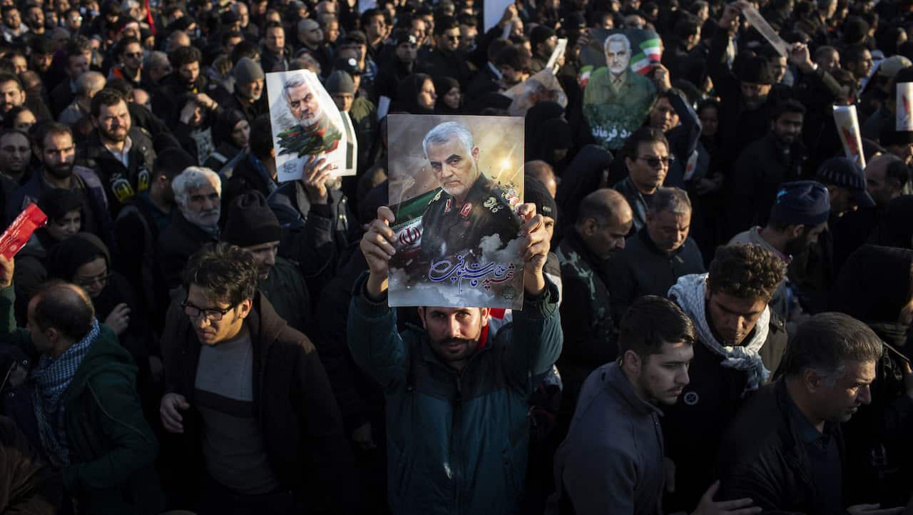 Iranian mourners hold Iran's national flag and religious flags as they attend the funeral procession of slain Iranian military commander Qasem Soleimani.
