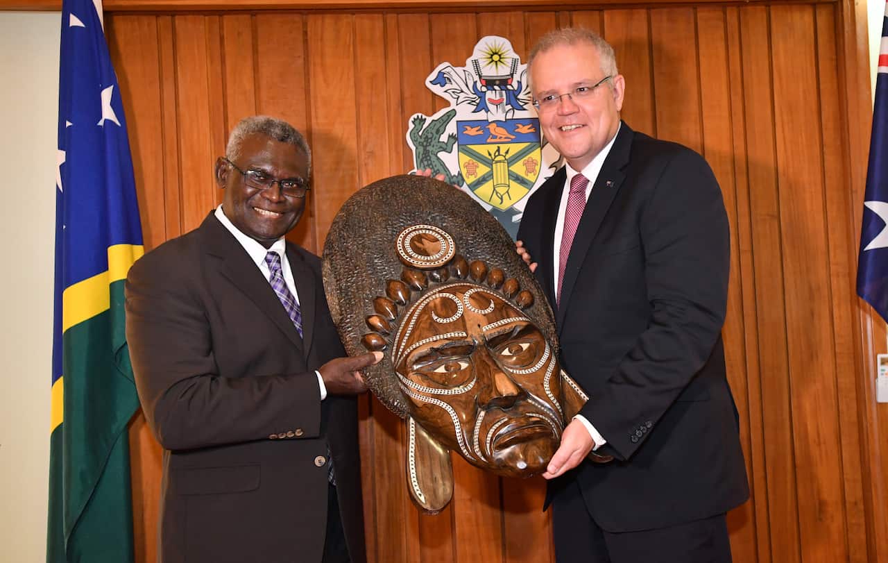 Solomon Islands Prime Minister Manasseh Sogavare (left) presents a traditional wood carving to the Australian Prime Minister Scott Morrison.