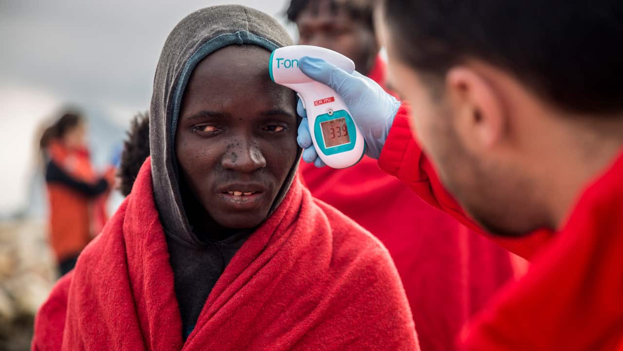 A volunteer takes the temperature of a migrant after disembarking from the Spanish NGO Proactiva Open Arms on December 28, 2018. 