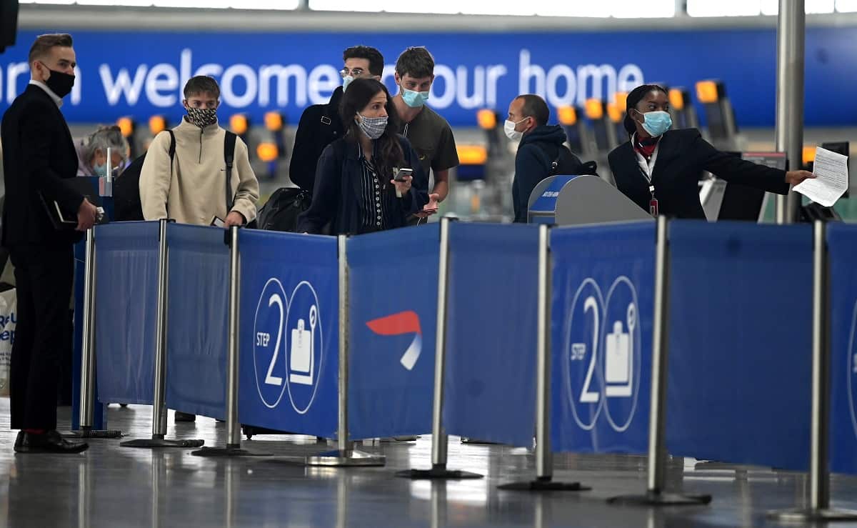 Passengers wearing face masks or covering due to the COVID-19 pandemic, queue at a British Airways check-in desk at Heathrow Airport.