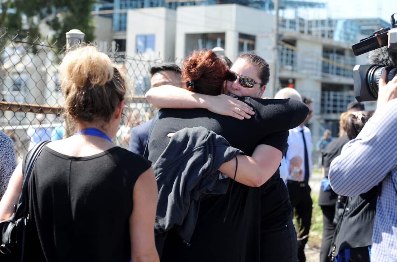 Spotlight employees comfort each other at the scene where a light plane crashed into the back of a DFO building at Essendon (AAP)