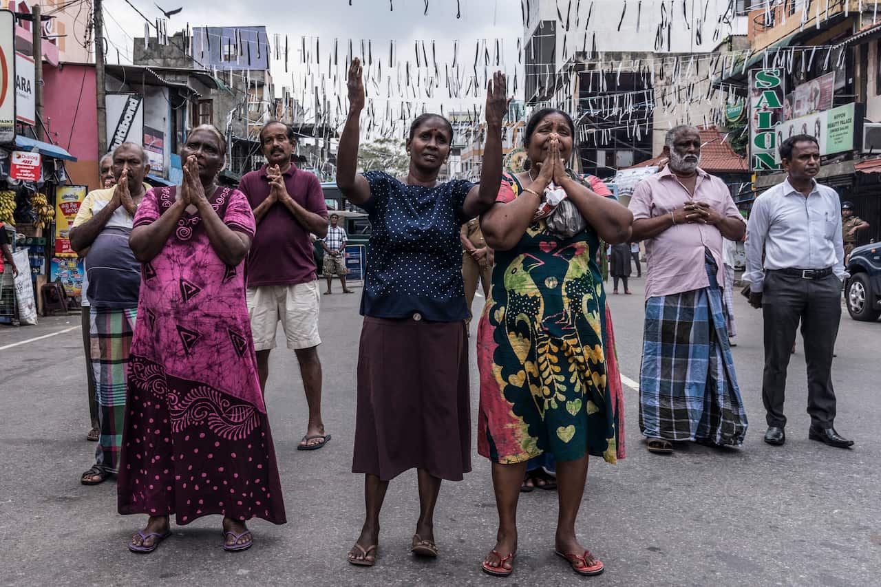People pray on the street near St. Anthony's Shrine in Colombo, Sri Lanka.