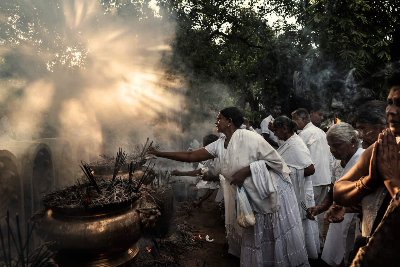 Buddhist worshippers light incense and pray at a temple in Colombo, Sri Lanka.