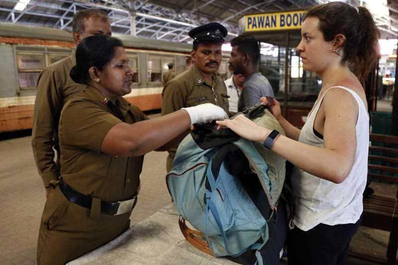 Sri Lankan security personnel check a foreign passenger while entering the Fort railway station in Colombo.
