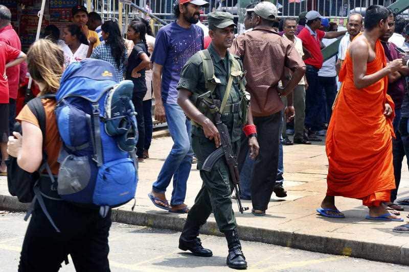 A backpacker walks through May Day celebrations as security forces look on.