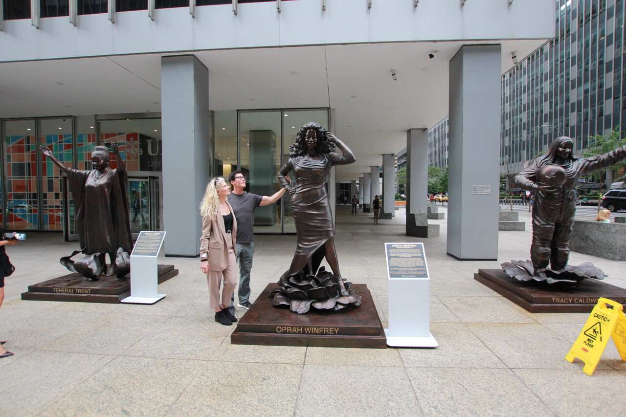 Gillie and Marc Schattner pose with their statues in New York City.