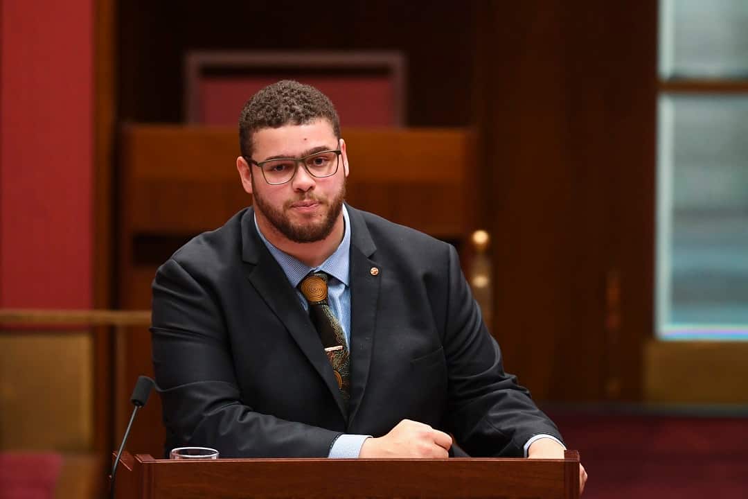 Man in suit at lectern.