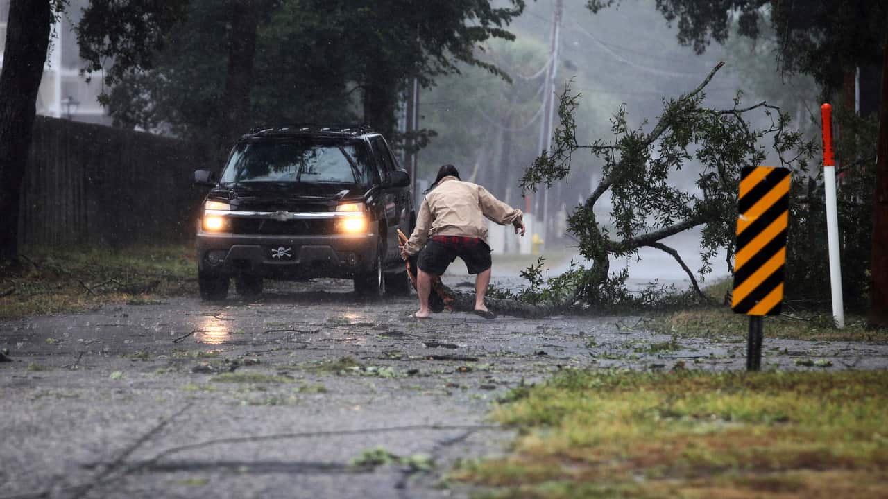 A man moves a large tree limb that downed power lines in North Myrtle Beach's Cherry Grove community.
