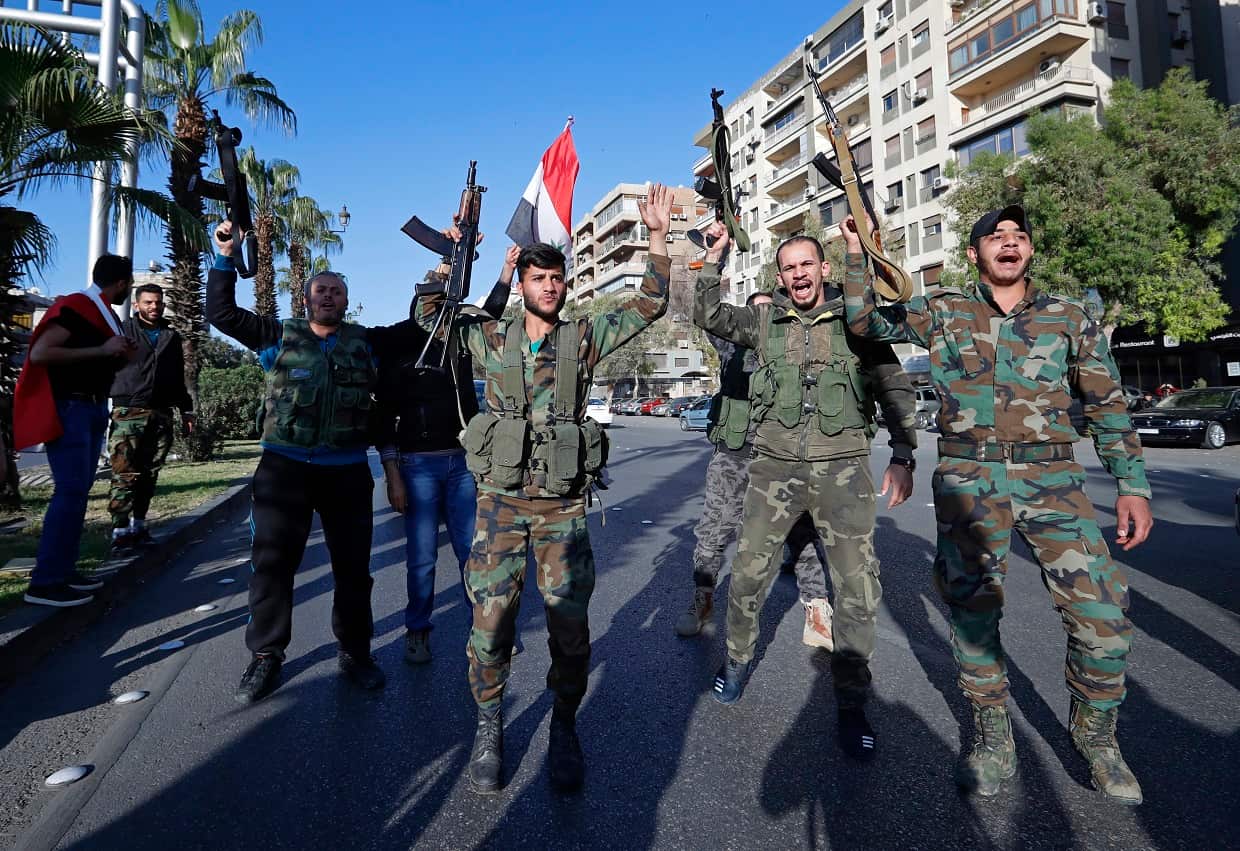 Syrian soldiers dance and chant slogans during demonstrations against the strikes.