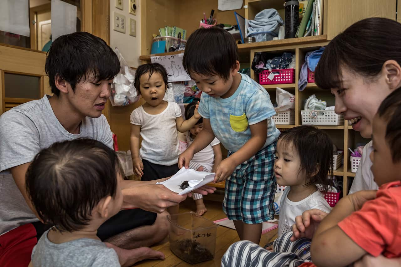 A nursery teacher introduces a bug to his young class at Midorigaoka Nursery School, in Tokyo.