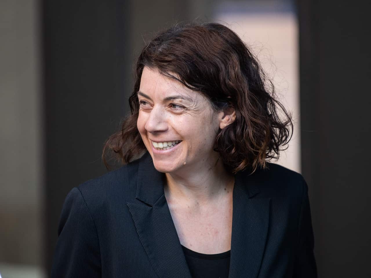 A woman smiling in a black blazer.