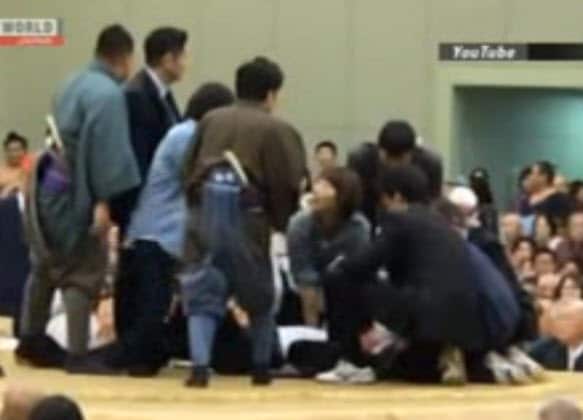 A woman performs CPR on the local mayor in the sumo ring. 