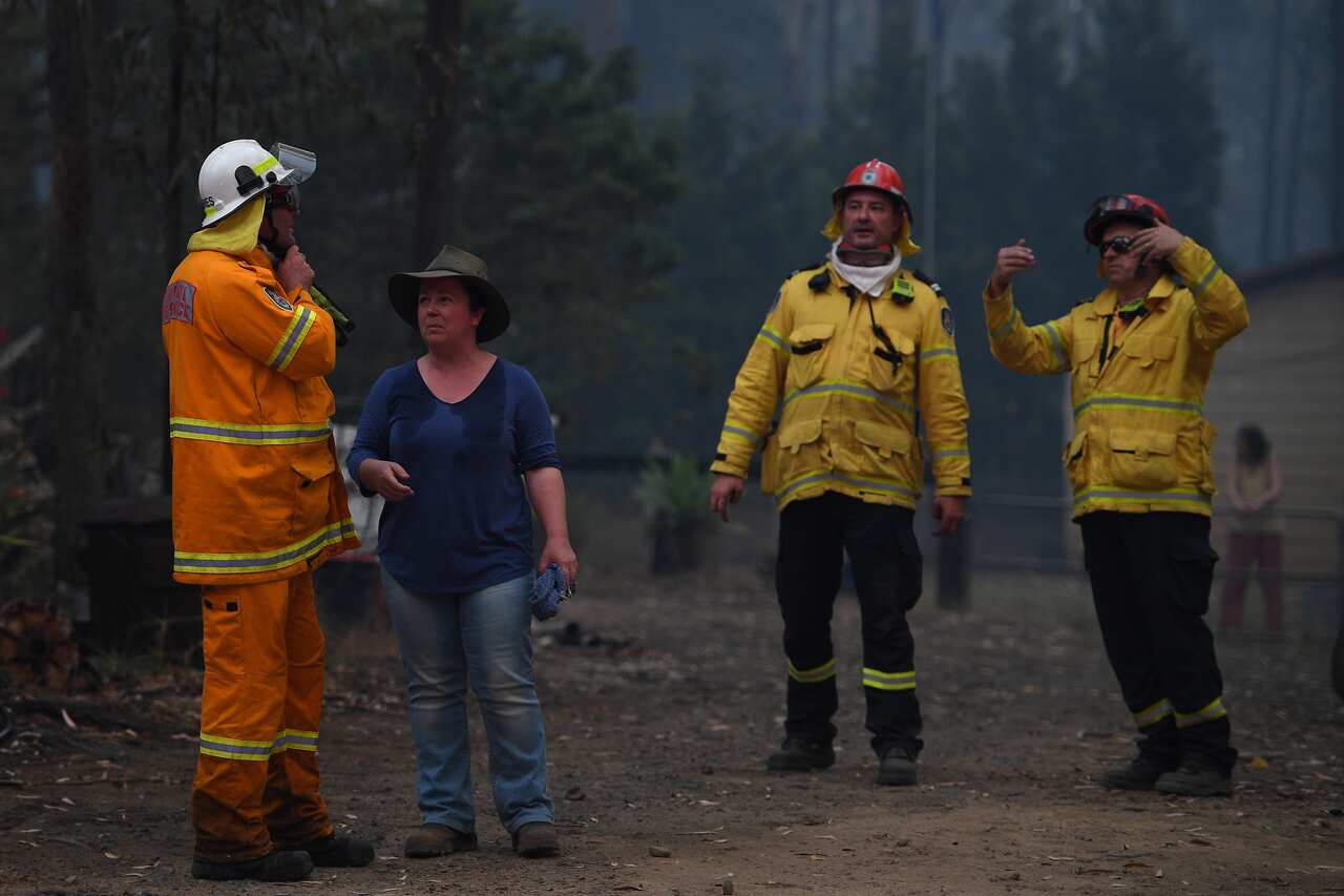 NSW Rural Fire Service crews speak to a resident as they fight a fire as it burns close to property on Wheelbarrow Ridge Road at Colo Heights.