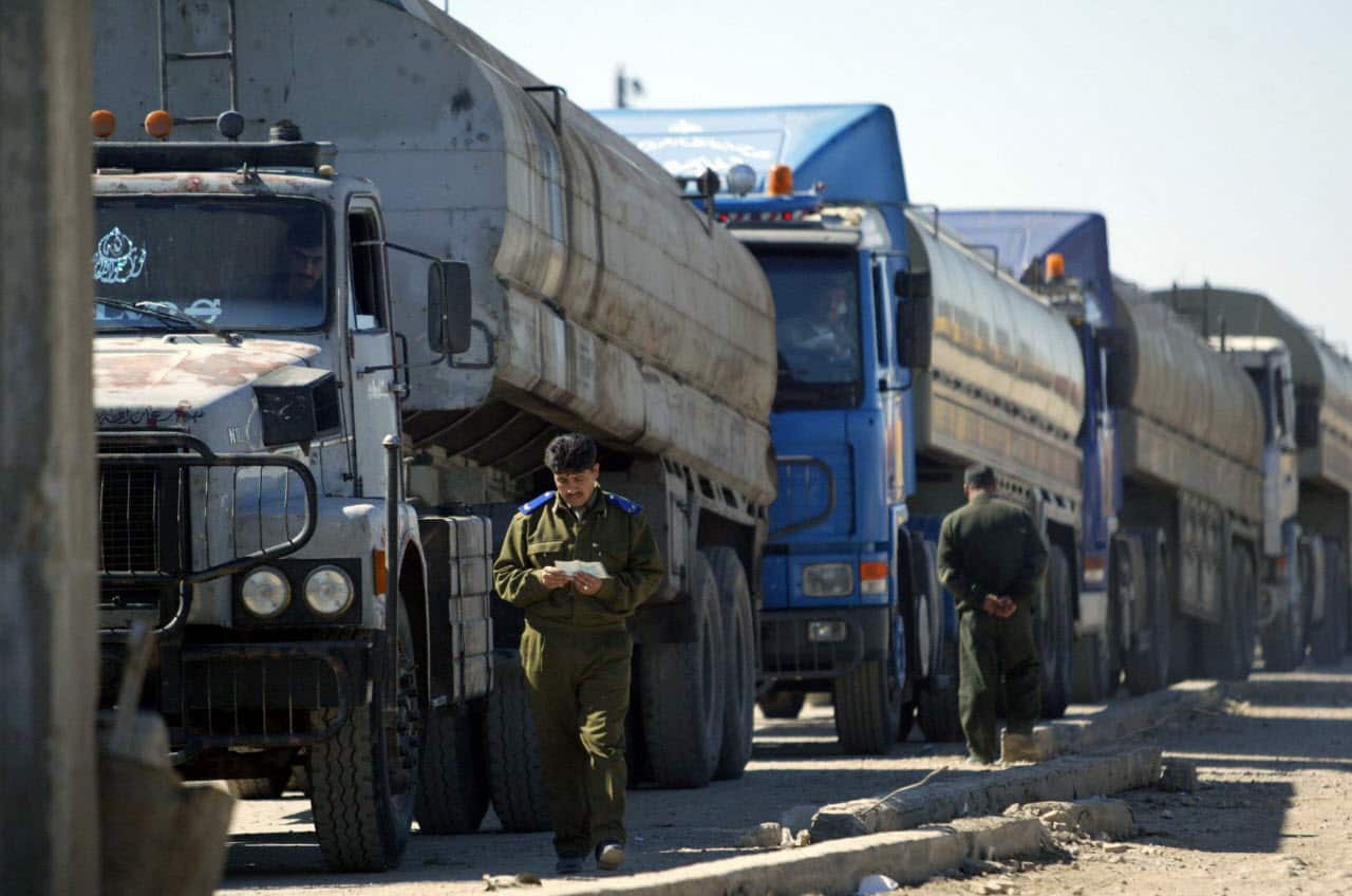 A Syrian policeman checks the papers of a fuel tanker truck driver before he lets him cross into Iraq from Syria at a border checkpoint in March 2004. 